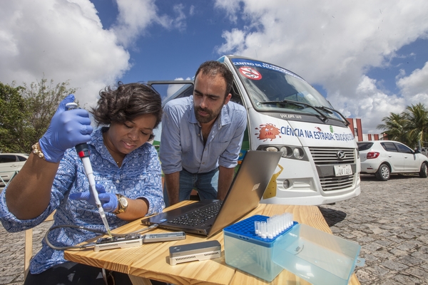 Foto de dois cientistas utilizando um sequenciador portátil a ceu aberto